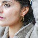 Boucles Eclipse Eight Ounce portées, apportant une touche moderne et minimaliste au look.